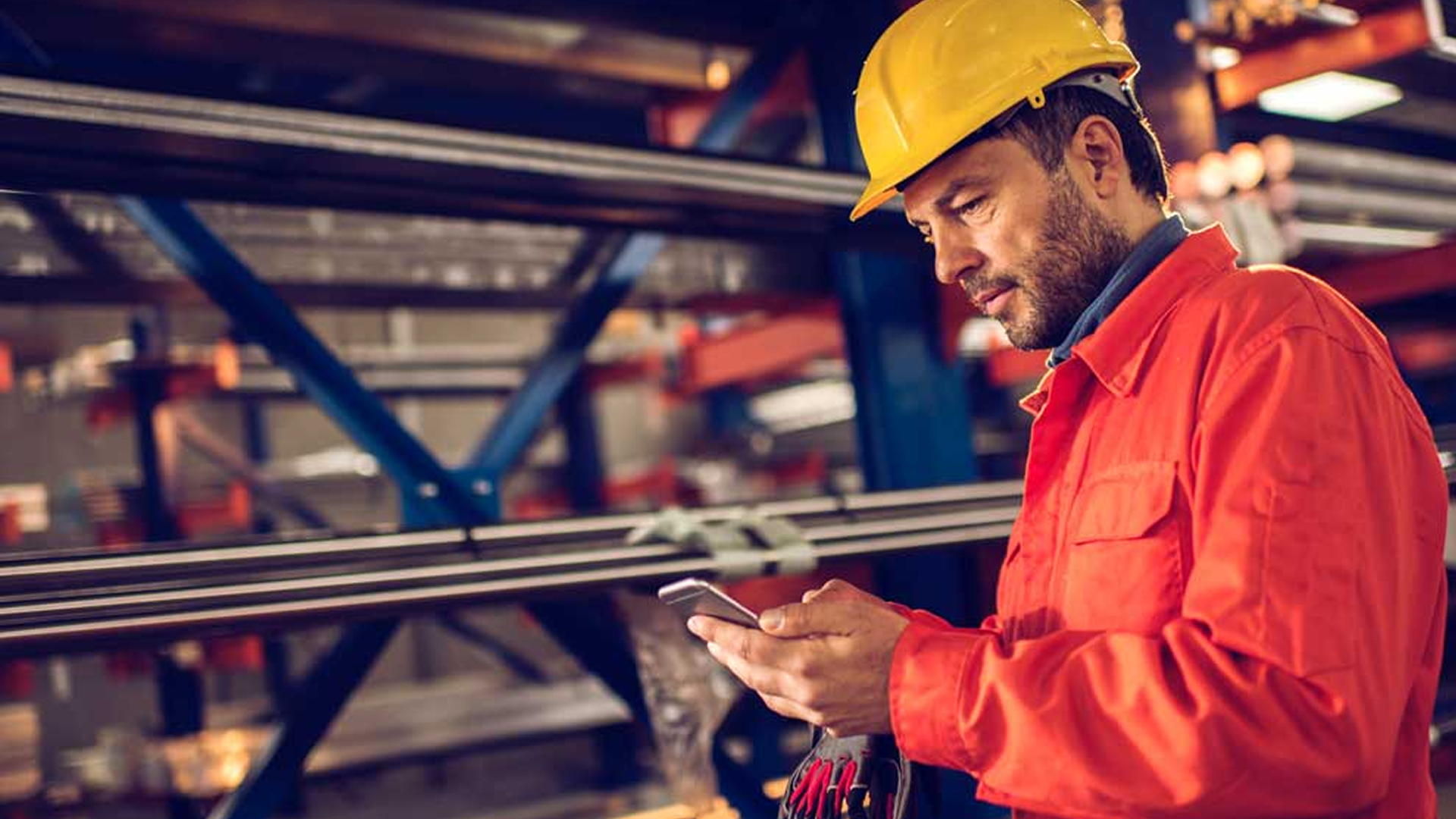 Industrial worker surronded by steel checking his phone